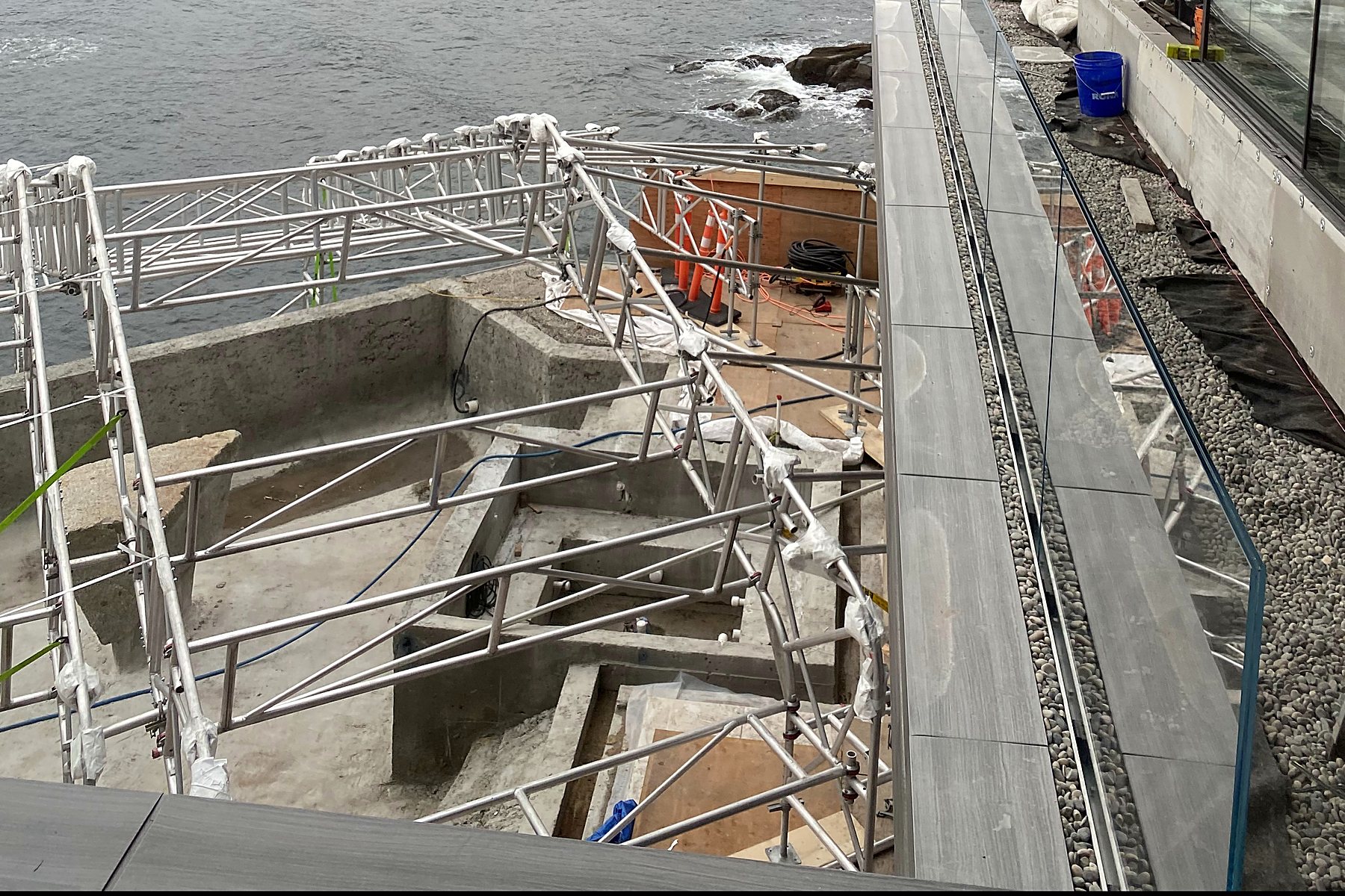 Glass railings along a waterfront walkway under construction