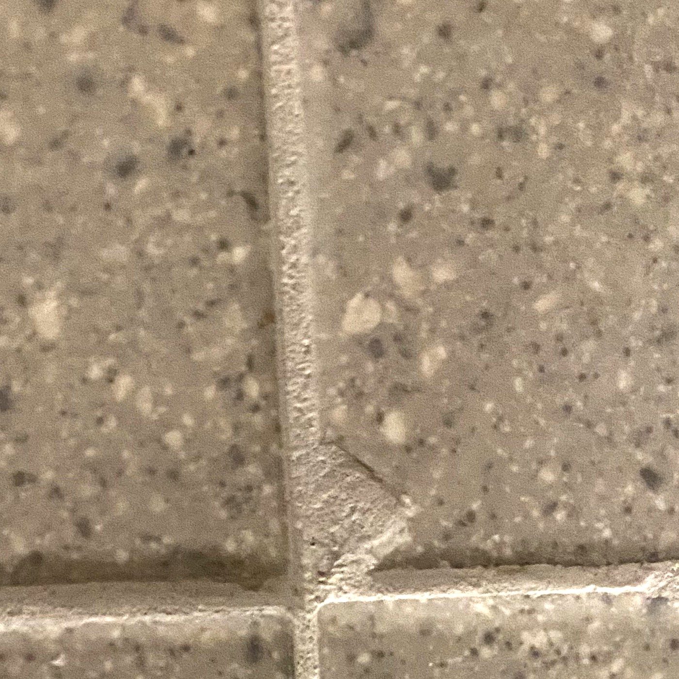 Before: speckled wall tile with a chipped corner