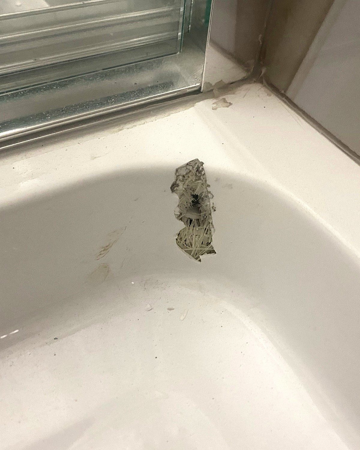 Before: bathtub with a large impact chip near the shower door