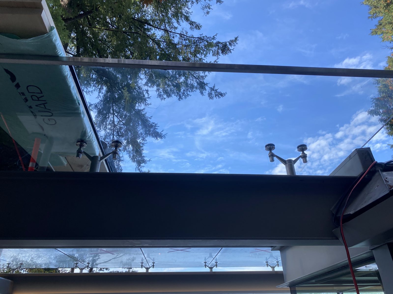 Overhead glass canopy panels on steel supports, seen from below