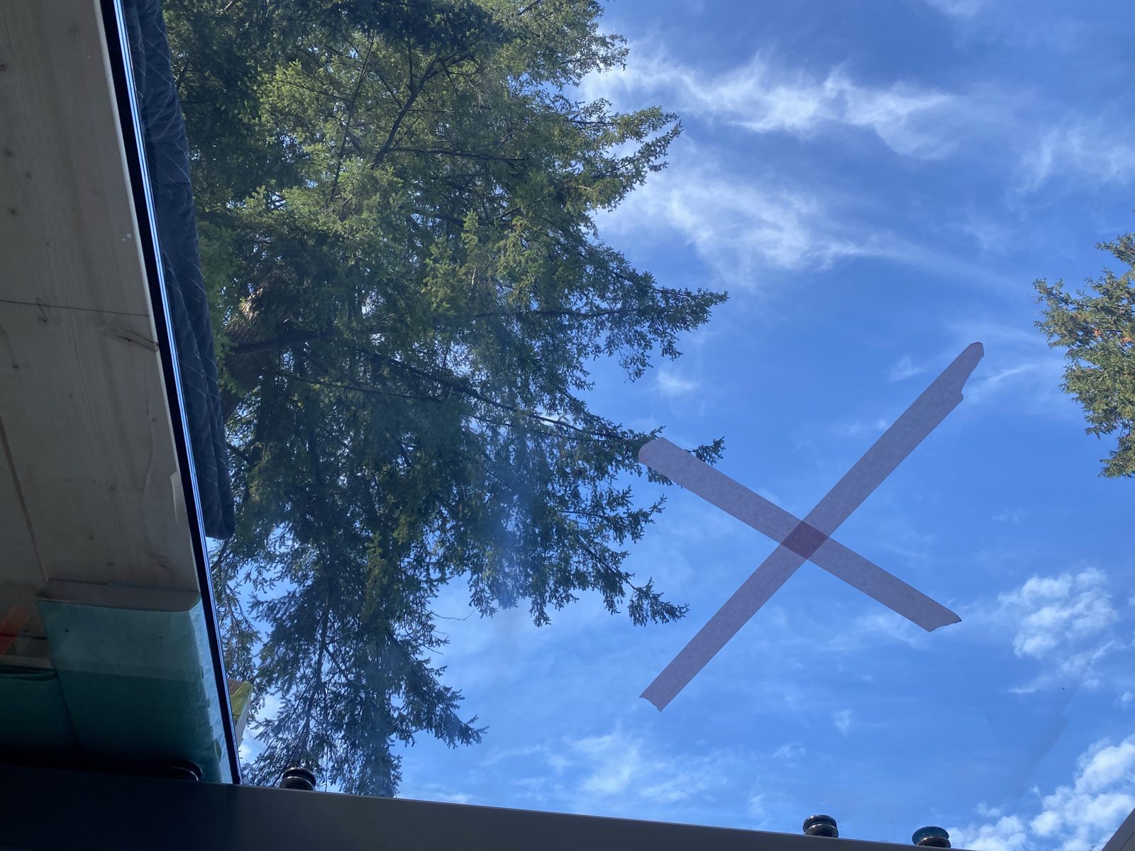 Tape X marking a scratch on overhead canopy glass against the sky